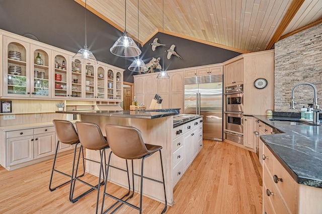 kitchen featuring hanging light fixtures, light wood-type flooring, stainless steel appliances, sink, and a kitchen island