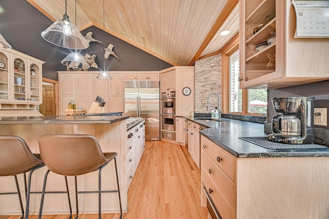 kitchen featuring light hardwood / wood-style flooring, decorative light fixtures, appliances with stainless steel finishes, sink, and lofted ceiling