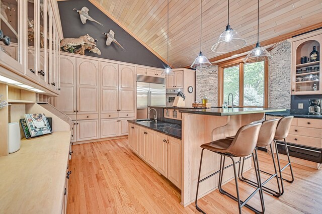 kitchen featuring wooden ceiling, light hardwood / wood-style flooring, stainless steel appliances, a kitchen breakfast bar, and a kitchen island with sink