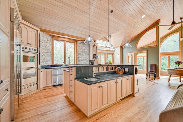 kitchen featuring decorative light fixtures, light wood-type flooring, and a kitchen island with sink