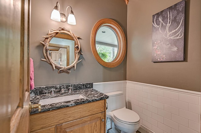 bathroom with vanity, toilet, and tile walls