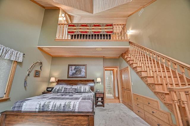 bedroom featuring wood ceiling, crown molding, carpet, and a high ceiling