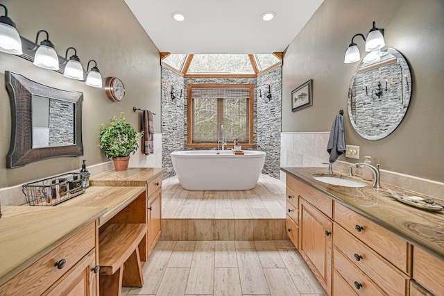 bathroom with a tub, vaulted ceiling, vanity, wood-type flooring, and tile walls