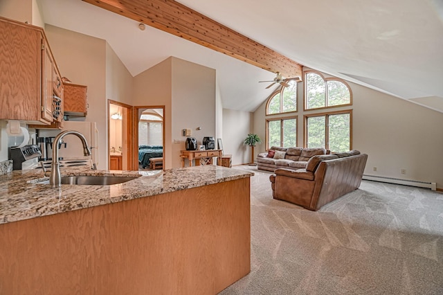 kitchen with light colored carpet, light stone counters, baseboard heating, sink, and ceiling fan