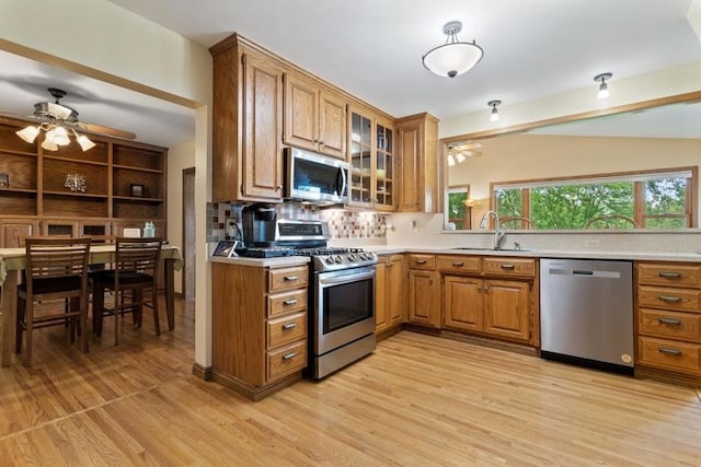 kitchen featuring stainless steel appliances, ceiling fan, sink, and light wood-type flooring