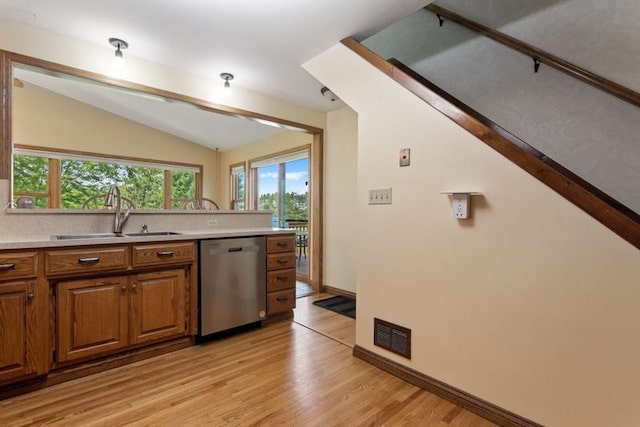 kitchen with vaulted ceiling, sink, stainless steel dishwasher, and light hardwood / wood-style floors