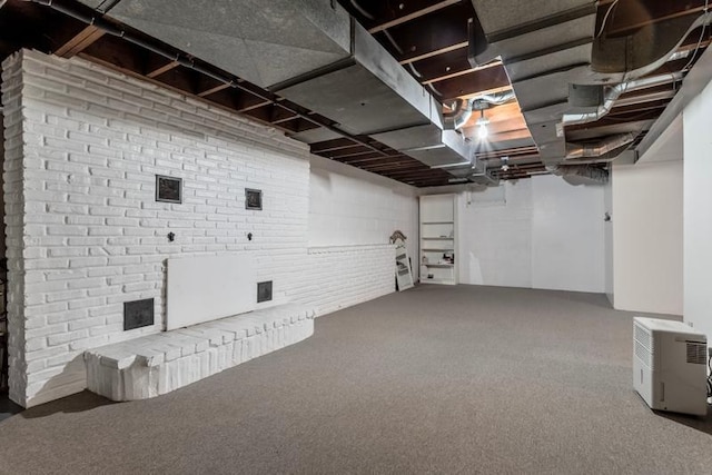 basement featuring brick wall and carpet floors