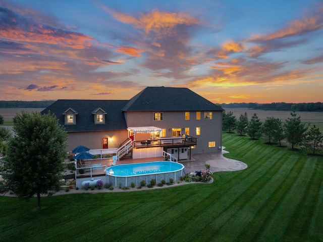 back house at dusk with a swimming pool side deck, a yard, and a patio