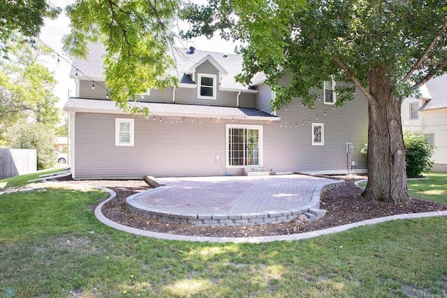 back of property featuring a shingled roof, a lawn, and a patio area