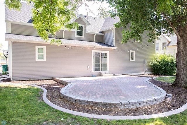 rear view of house featuring a shingled roof, a lawn, and a patio area