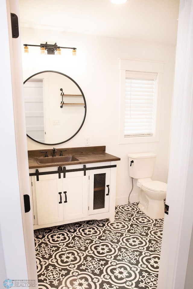 half bathroom featuring vanity, toilet, and tile patterned floors