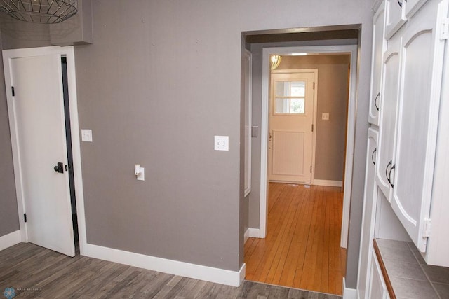 corridor featuring baseboards and wood finished floors