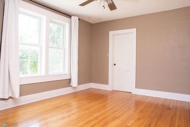 unfurnished room with light wood finished floors, baseboards, and a ceiling fan