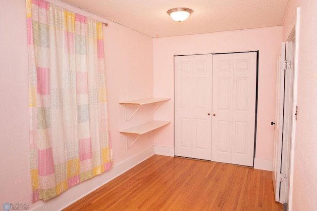 unfurnished bedroom featuring a closet, light wood-style flooring, and baseboards