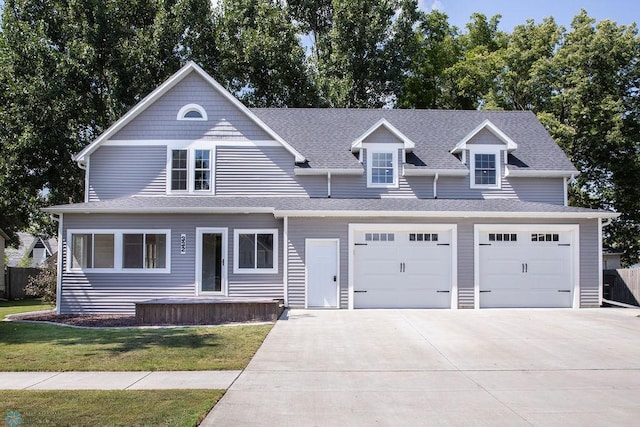 view of front facade featuring driveway, roof with shingles, and a front yard