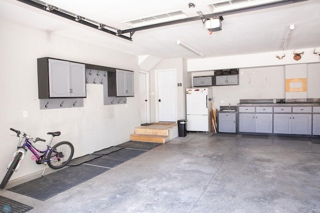 garage featuring a garage door opener, freestanding refrigerator, and visible vents