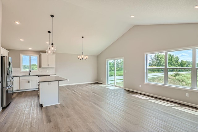 kitchen with light hardwood / wood-style floors, white cabinets, decorative light fixtures, stainless steel refrigerator with ice dispenser, and sink