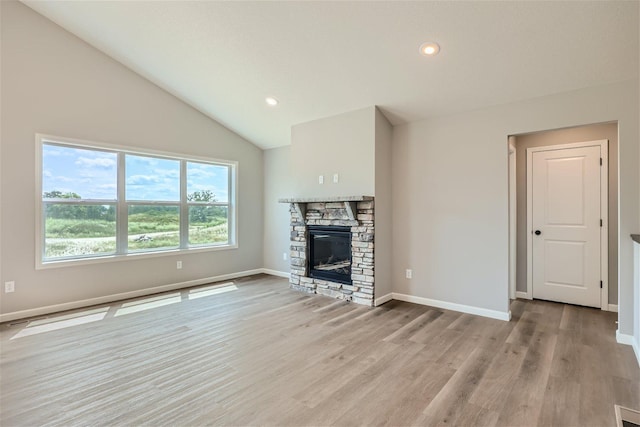 unfurnished living room featuring high vaulted ceiling, light hardwood / wood-style floors, and a stone fireplace