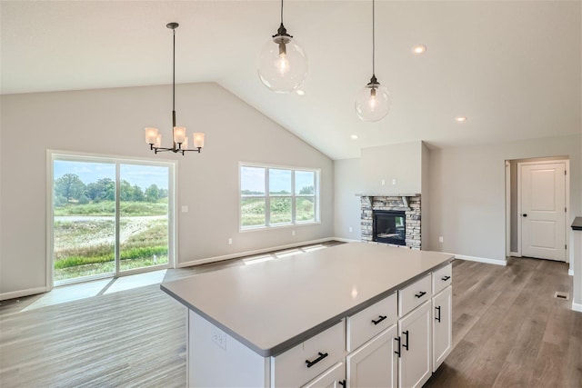 kitchen featuring pendant lighting, a kitchen island, white cabinetry, a fireplace, and light hardwood / wood-style floors