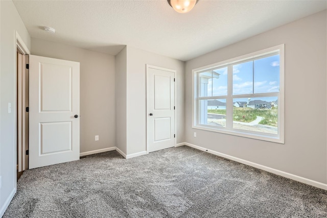 unfurnished bedroom featuring carpet floors, a textured ceiling, and a closet