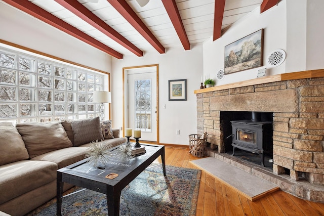 living room featuring hardwood / wood-style flooring, a wood stove, baseboards, and beam ceiling