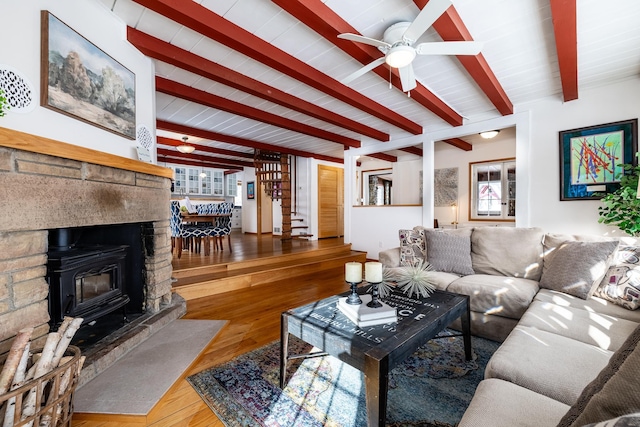 living room featuring beam ceiling, stairway, ceiling fan, and wood finished floors