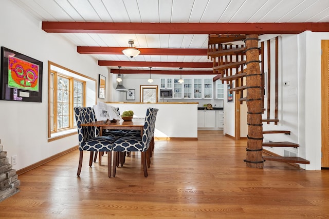 dining room featuring baseboards, stairway, light wood-type flooring, beam ceiling, and wooden ceiling