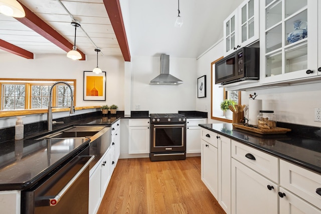 kitchen featuring plenty of natural light, high end stainless steel range oven, black microwave, and wall chimney range hood