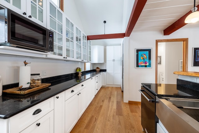 kitchen featuring light wood finished floors, glass insert cabinets, pendant lighting, white cabinetry, and beamed ceiling