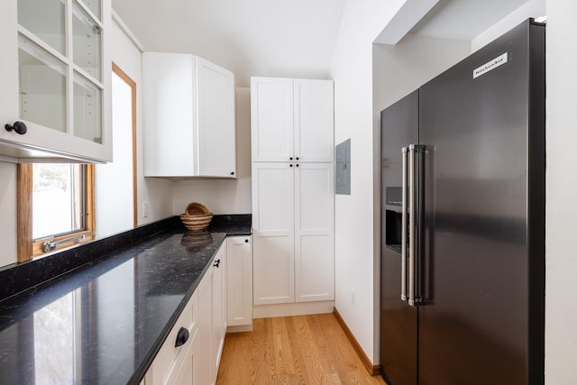 kitchen with dark stone counters, high quality fridge, light wood-style flooring, and white cabinetry