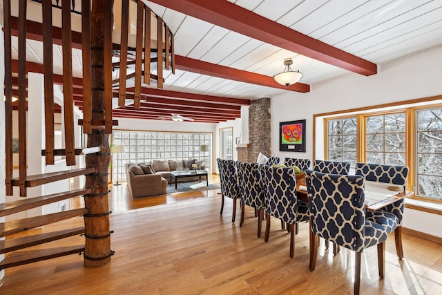 dining area featuring beam ceiling, light wood-style flooring, and baseboards