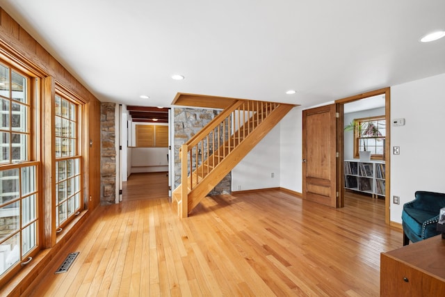 unfurnished living room featuring visible vents, baseboards, stairway, recessed lighting, and light wood-style flooring