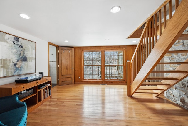 living area featuring stairway, recessed lighting, light wood-type flooring, and wooden walls