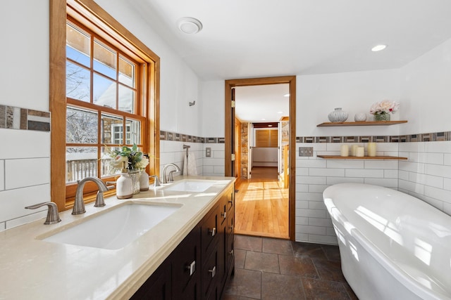 full bath featuring a sink, a soaking tub, and tile walls