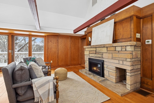 living room with light wood-type flooring, visible vents, and a fireplace