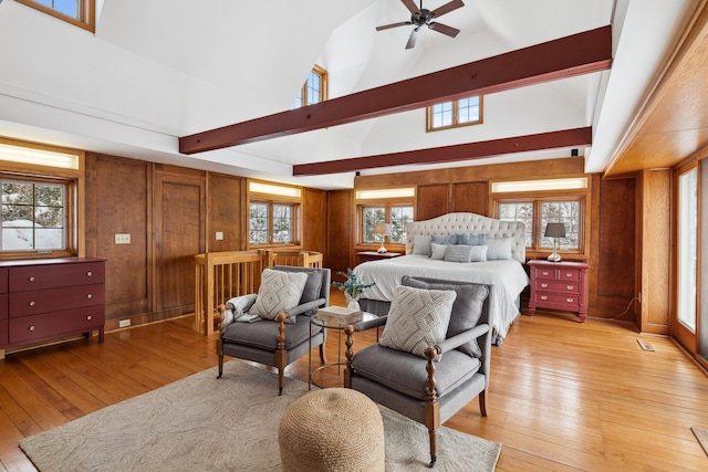 bedroom featuring light wood-type flooring, wooden walls, and high vaulted ceiling