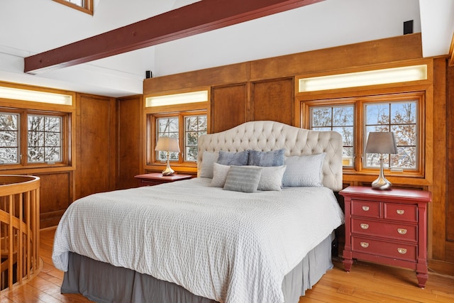 bedroom with light wood-type flooring, beam ceiling, and wooden walls