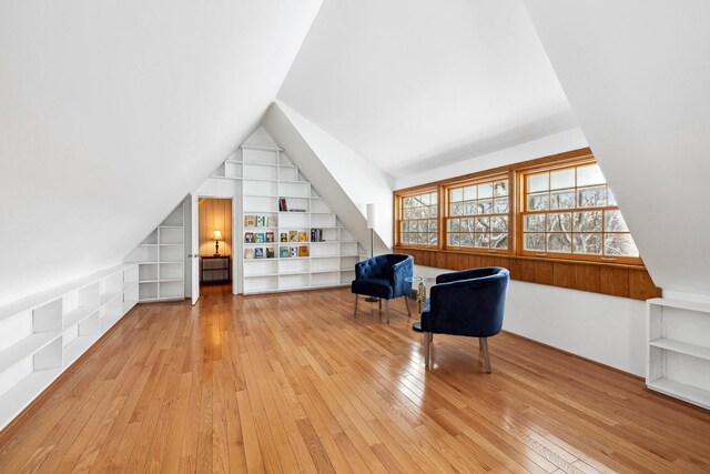 unfurnished room featuring lofted ceiling, built in shelves, and light wood-style floors