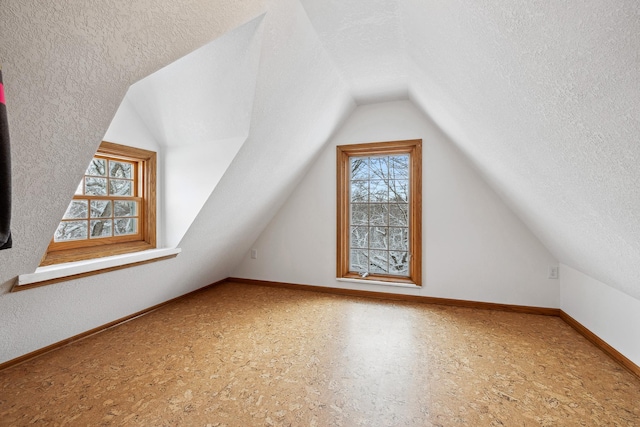 bonus room with baseboards, lofted ceiling, and a textured ceiling