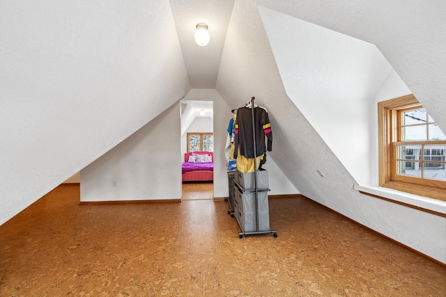 additional living space featuring baseboards, plenty of natural light, lofted ceiling, and a textured ceiling