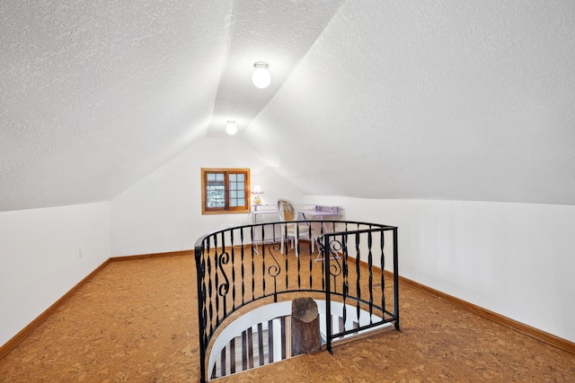 bonus room with a textured ceiling, baseboards, and lofted ceiling