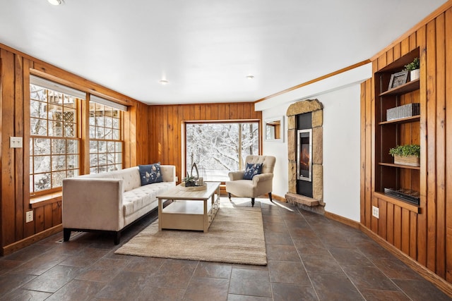 living room featuring stone finish floor, built in features, baseboards, and wood walls