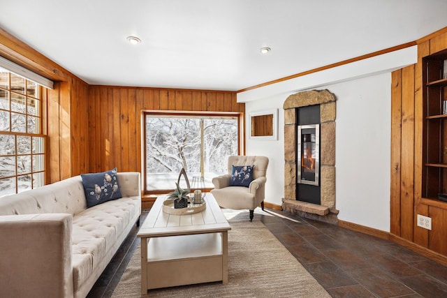 living room with stone finish floor, wood walls, a fireplace, and baseboards