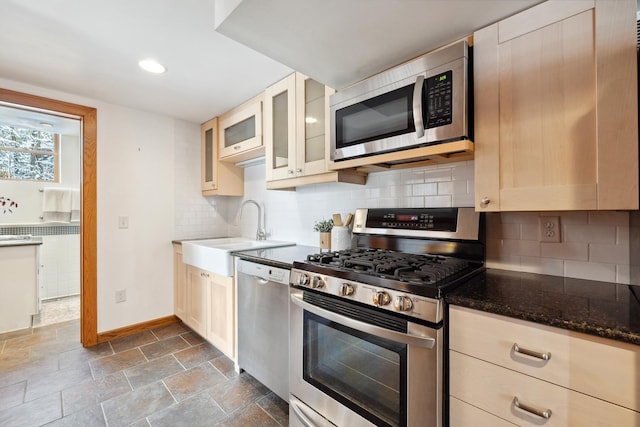 kitchen featuring dark stone countertops, baseboards, stainless steel appliances, glass insert cabinets, and tasteful backsplash