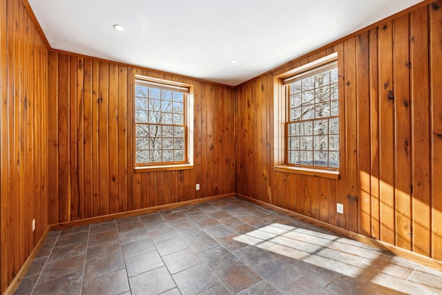 empty room with wood walls, stone finish flooring, and baseboards