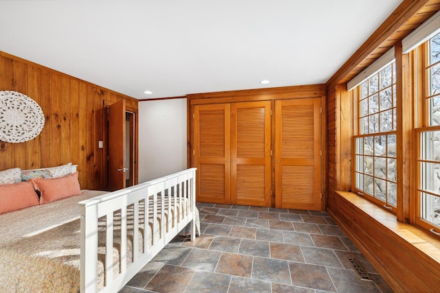 bedroom with wooden walls, recessed lighting, and stone finish floor