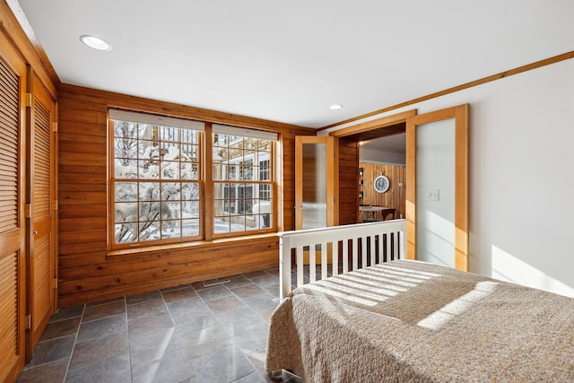 unfurnished bedroom with recessed lighting, a closet, wood walls, and stone tile flooring