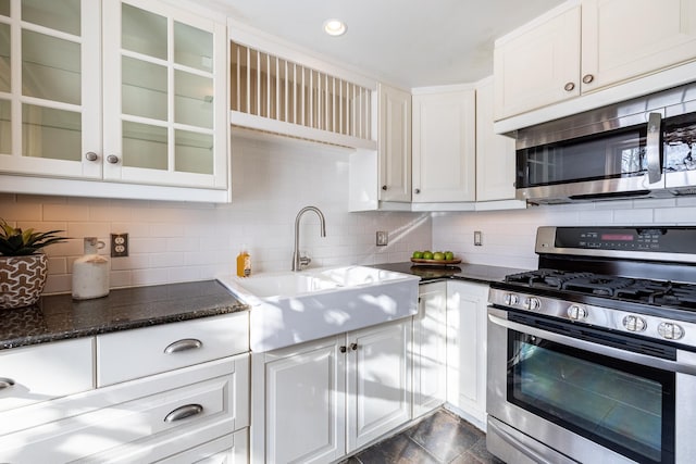 kitchen featuring decorative backsplash, white cabinets, stainless steel appliances, and a sink