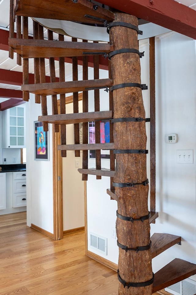 stairway with visible vents, baseboards, and wood finished floors