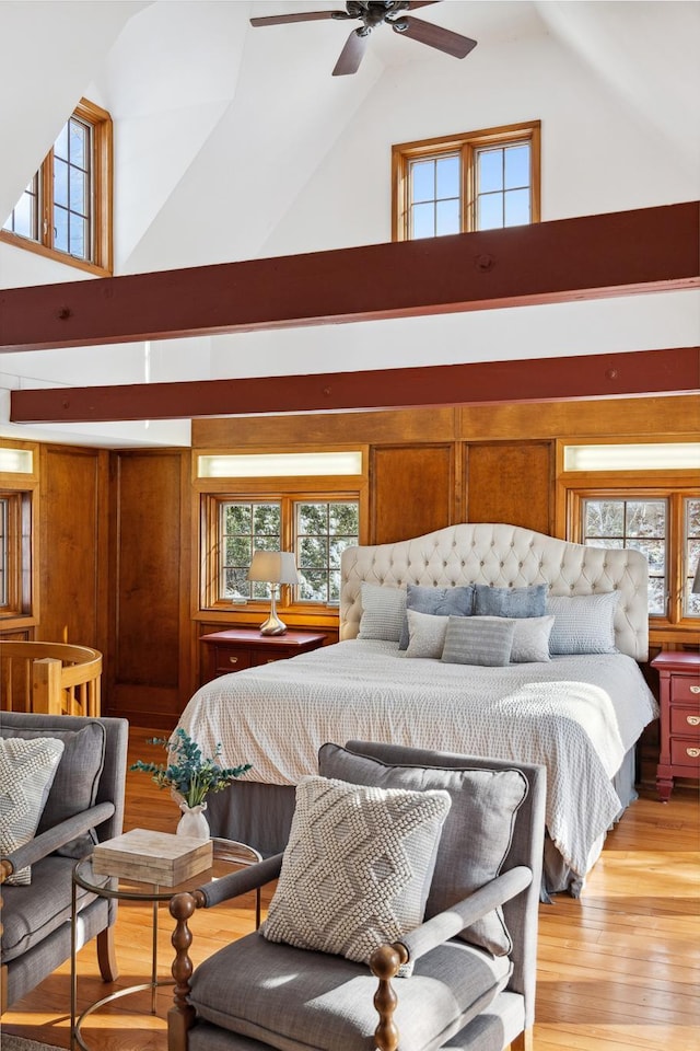 bedroom with a towering ceiling, light wood-type flooring, and wood walls